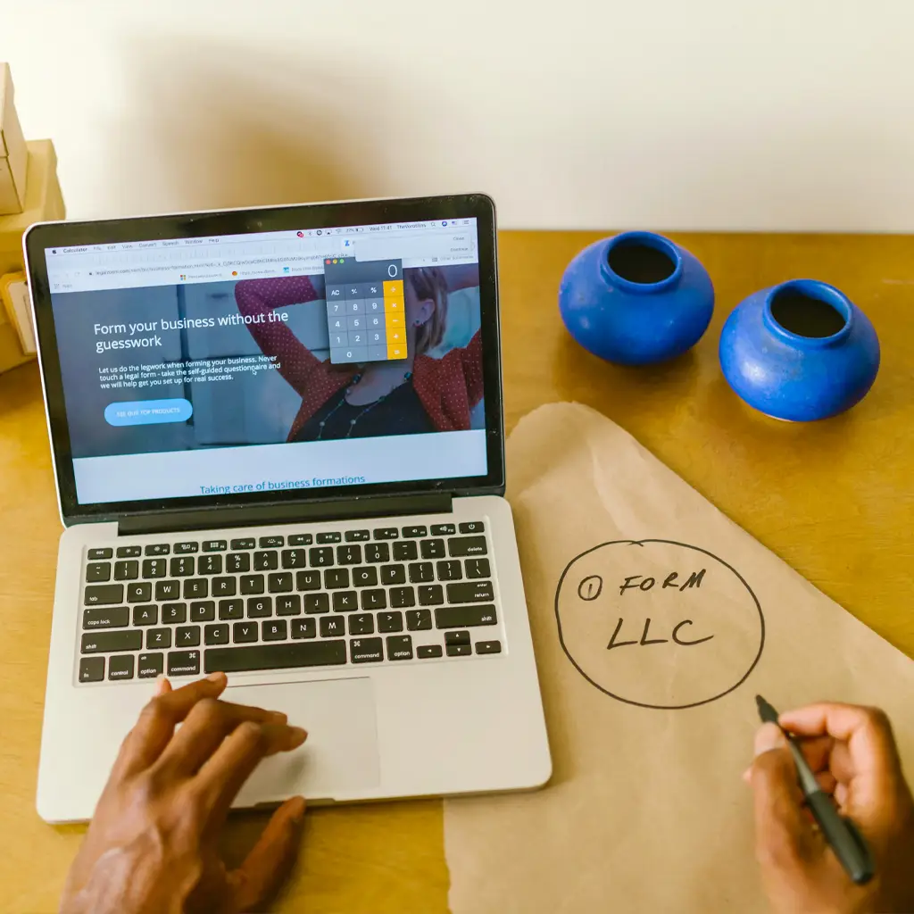 A desk with a laptop and a piece of paper that says "form an LLC"