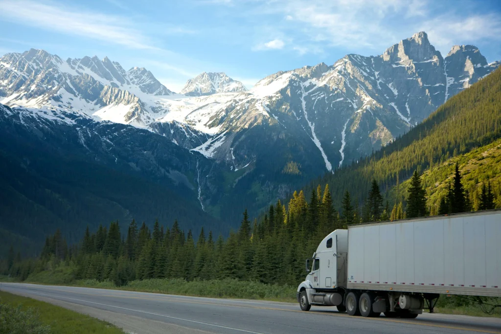 A semi truck driving up a road with a mountain view